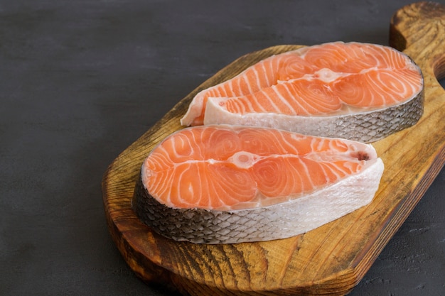 Peixe cru de bife de salmão preparado para cozinhar. Vista superior na mesa preta.