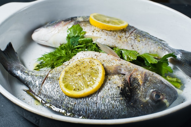 Peixe cru Dorado marinado em azeite, sal e pimenta, uma fatia de limão por cima.