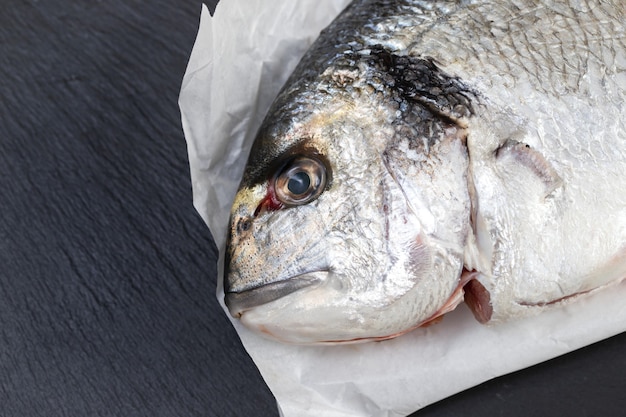 Peixe cru em papel branco na mesa de cerâmica