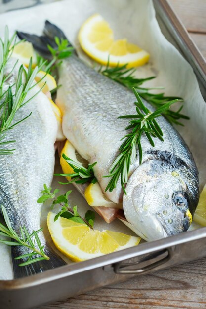 Peixe cru fresco dorado dorado do mar cru com limão alecrim orégano ervas azeite na mesa da cozinha