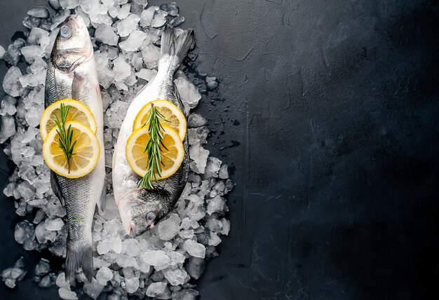 peixe cru fresco robalo e dorado com limão e alecrim no gelo, sobre um fundo de pedra