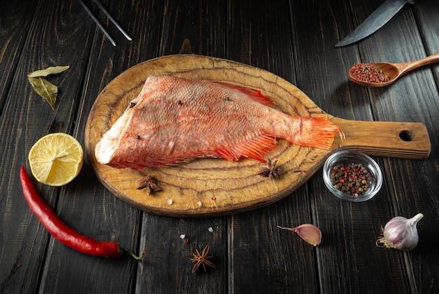 Peixe cru Sebastes na tábua de cozinha antes de cozinhar com especiarias aromáticas pimenta e limão