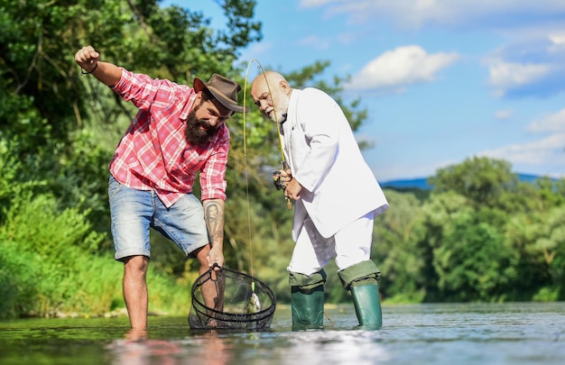 Peixe de água doce homem barbudo e pesca hipster brutal oh dia feliz equipe de pesca dia da família hobby e recreação pegar peixe com alma gêmea amigos pegando peixe peixe preso na rede