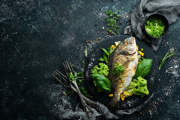 Peixe Dorado assado com arroz e legumes em um prato preto Vista superior Espaço livre para o seu texto