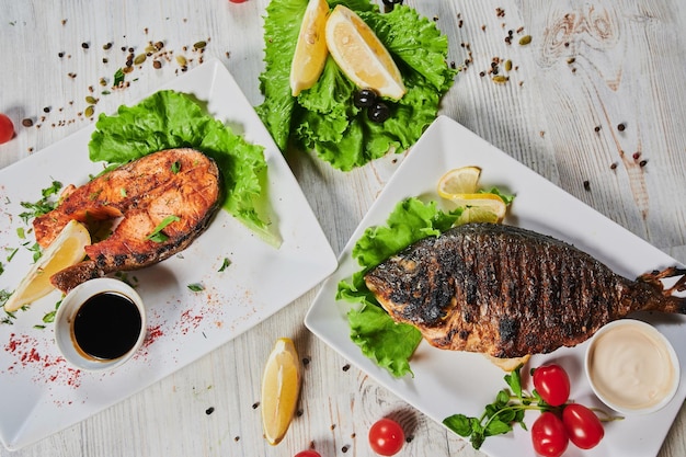 Foto peixe dorado decorado com legumes, ervas e limão num prato