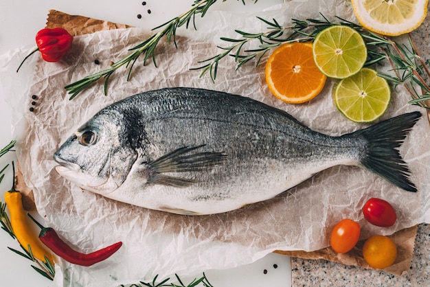 Peixe dourada dourada na assadeira com alecrim, limão, laranja, tomate, pimenta e limão