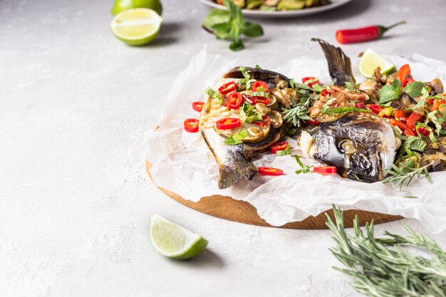 Peixe dourado assado com limão, frio, ervas e legumes