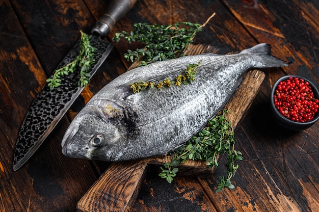 Peixe dourado cru em uma tábua com faca