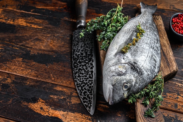 Peixe dourado cru em uma tábua com faca