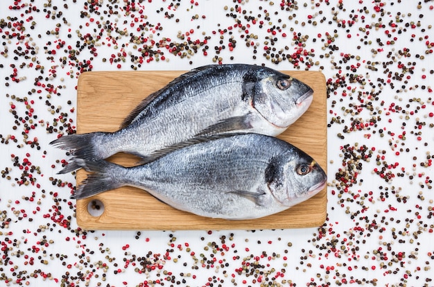 Peixe dourado cru na tábua de madeira. vista superior, copie o espaço