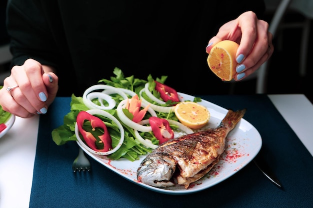 Peixe dourado de cupra frito na chapa branca com rúcula de jardim de cebola e rodelas de limão