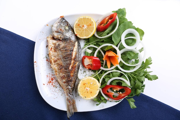 Peixe dourado de cupra frito na chapa branca com rúcula de jardim de cebola e rodelas de limão