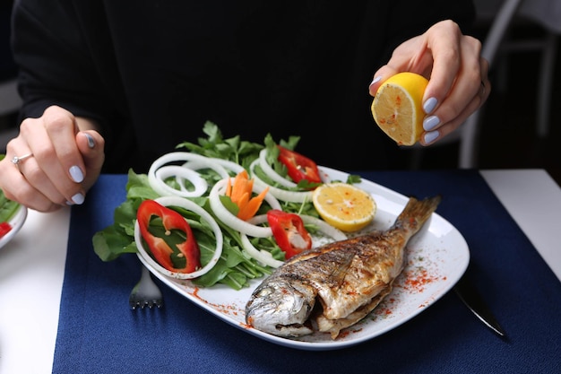 Peixe dourado de cupra frito na chapa branca com rúcula de jardim de cebola e rodelas de limão