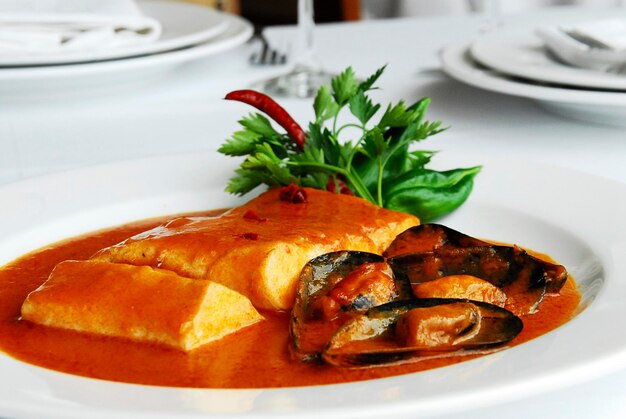 Peixe em molho de tomate e chipotle vermelho com mexilhões em uma mesa de restaurante gastronomia