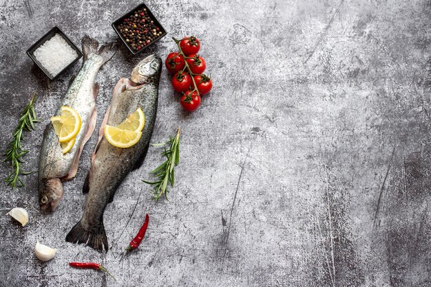 Foto peixe em um fundo cinza com tomates e limões