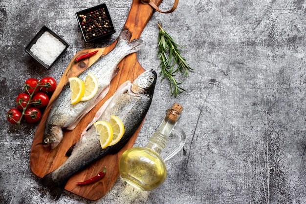 Peixe em uma tábua com limão, pimenta vermelha, alho e azeite.