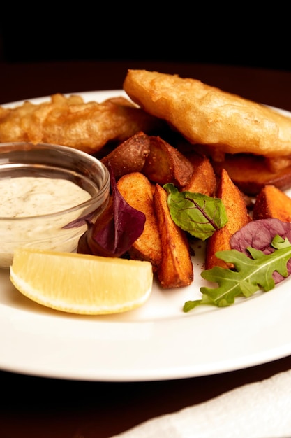 Peixe empanado em um prato com batatas fritas em uma mesa de madeira em comida insalubre de pub