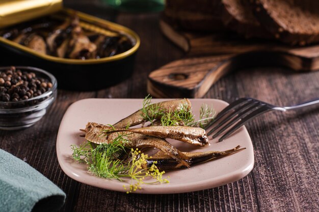 Peixe enlatado em óleo e endro num prato na mesa