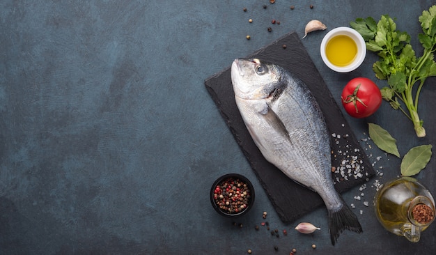 Peixe fresco com ervas e óleo de especiarias na tábua de corte preta