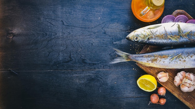 Peixe fresco com especiarias de legumes e óleo Em um fundo preto de madeira Espaço livre para texto Vista superior