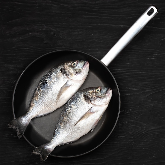 Foto peixe fresco dorado dorado e ingredientes para cozinhar em uma mesa