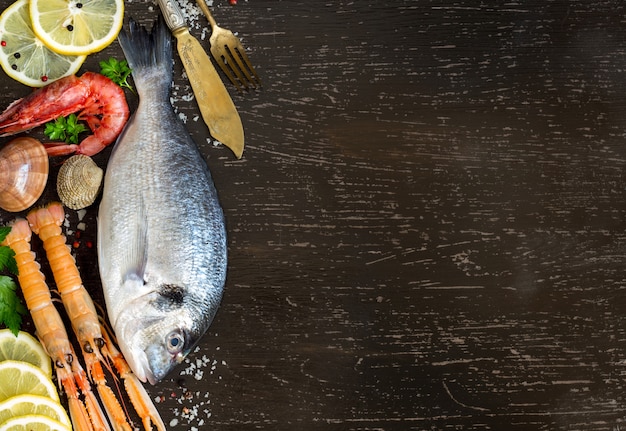 Peixe fresco dorado, frutos do mar, pedaços de limão e ervas