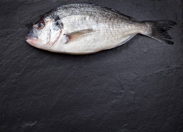 Peixe fresco dorado na mesa escura