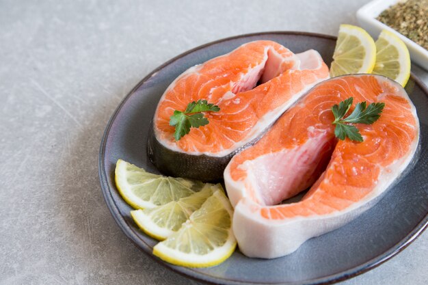 Peixe fresco. Filés de salmão fresco com limão, especiarias e sal em um prato escuro