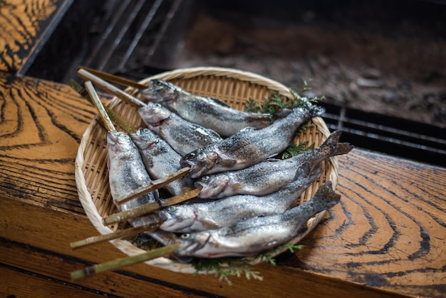 Peixe fresco iwana, preparando-se para churrasco tradicional japonês com vara de bambu espeto