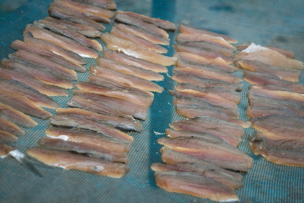 Peixe fresco na rede de plástico sob a luz do sol para fazer peixe seco