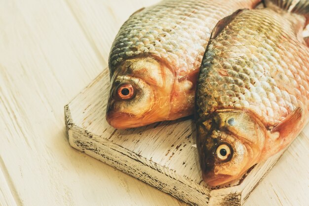 Peixe fresco. Peixe cru na mesa de madeira branca. Peixe em uma placa de cozinha de madeira branca sobre a mesa