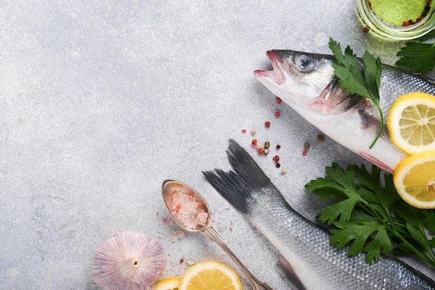 Peixe fresco Robalo cru com sal pimenta salsa azeite e limão na tábua no fundo rústico de concreto cinza claro Fundo de cozimento de alimentos Vista superior espaço de cópia