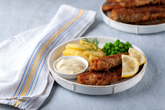 Peixe frito com batata frita, ervilha e limão