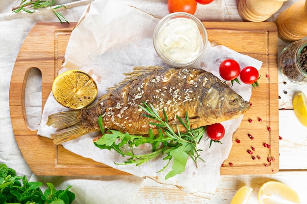 Peixe frito com legumes na mesa de madeira