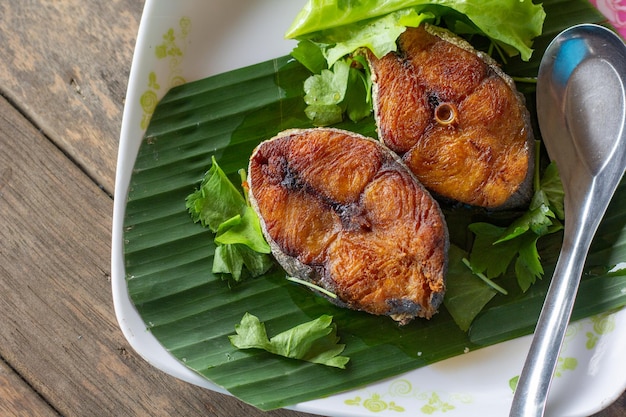 Peixe frito com molho de salada picante na mesa de madeira de perto