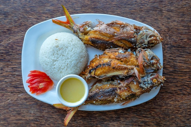 Peixe grelhado servido com molho de arroz e tomate close-up