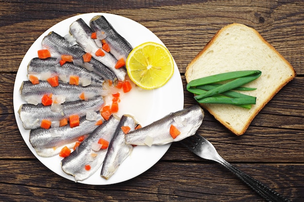 Peixe marinado em um prato na mesa de madeira vintage. Vista do topo