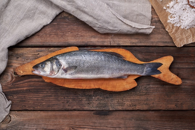 Peixe robalo inteiro fresco na tábua marrom