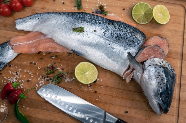 Peixe salmão cru fresco na placa de madeira da cozinha com especiarias e limão