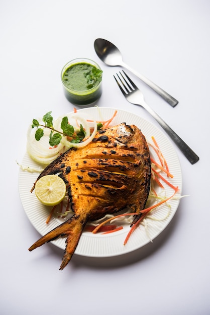 Peixe Tandoori Pomfret cozido em forno de barro e guarnecido com salada de limão, hortelã, couve e cenoura. Foco seletivo