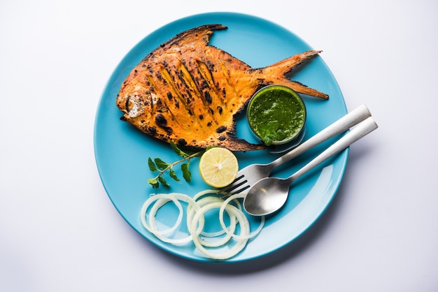 Peixe Tandoori Pomfret cozido em forno de barro e guarnecido com salada de limão, hortelã, couve e cenoura. Foco seletivo