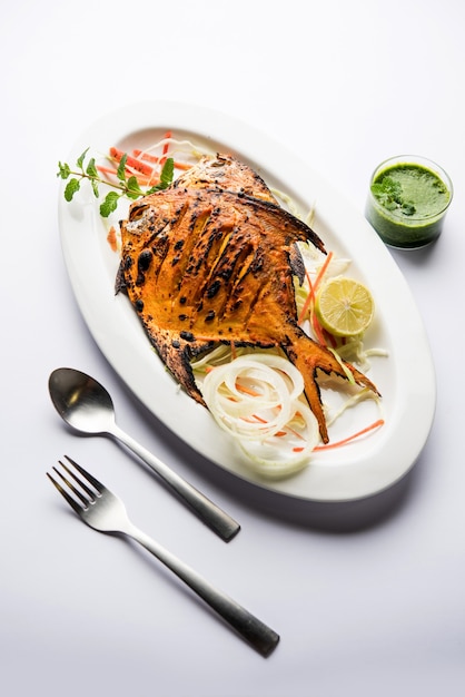 Peixe Tandoori Pomfret cozido em forno de barro e guarnecido com salada de limão, hortelã, couve e cenoura