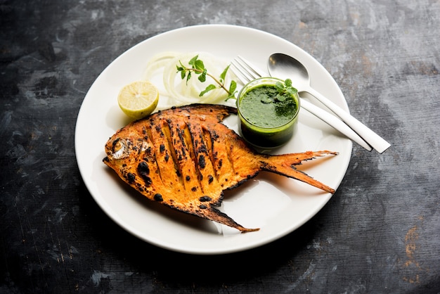 Peixe Tandoori Pomfret cozido em forno de barro e guarnecido com salada de limão, hortelã, couve e cenoura