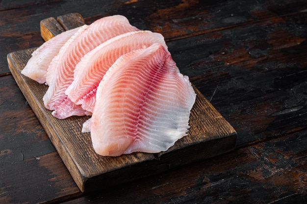 Foto peixe tilápia, carne sem pele, na velha mesa de madeira