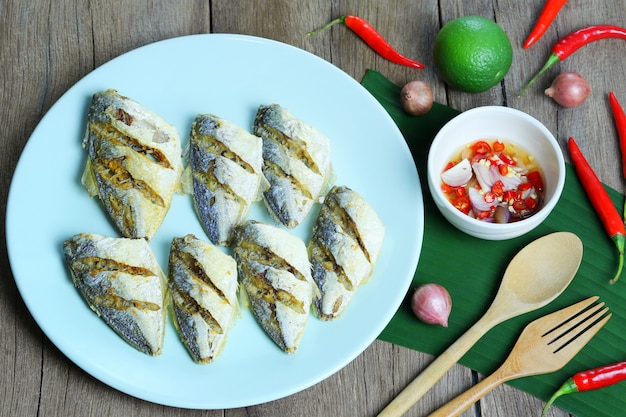 Peixes de mar fritado no molho da placa e de peixes com o picante na tabela do alimento.