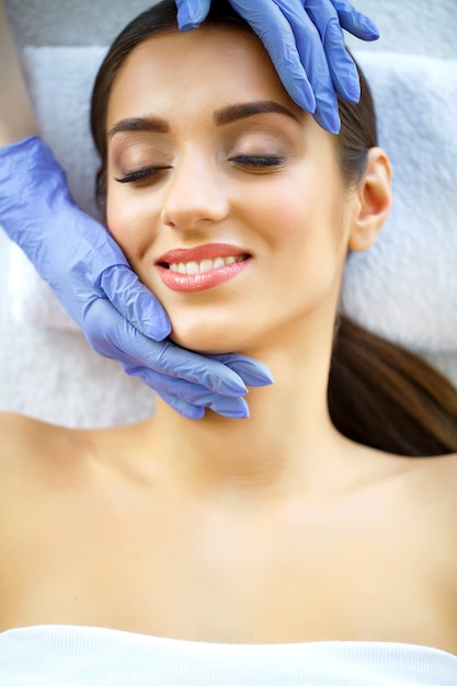 Pele e cuidados. Mulher jovem e bonita com pele pura e bonita no salão Spa. Massagem para o rosto. Deitado na mesa de massagem. Massagem Manual. Alta resolução