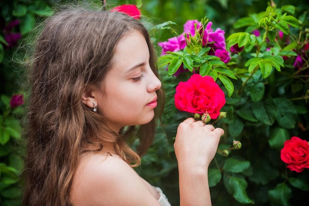 Pele perfeita da menina apreciando o aroma da flor rosa fecha o conceito de cosméticos naturais