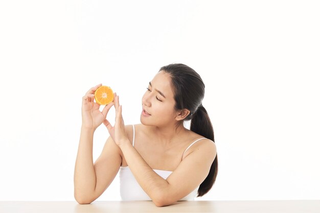 Pele perfeita e fresca. retrato de mulher jovem e bonita sorridente com laranja em fatias, isolada na superfície branca. conceito de mulher saudável