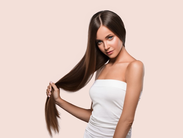 Pele saudável da mulher linda cabelo liso longo morena penteado. Cor de fundo. Cor de rosa