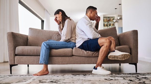 Pelea frustrada y pareja con un problema en su matrimonio en el sofá de la sala de estar de su casa Hombre y mujer tristes, enojados y deprimidos, pensando en un conflicto de divorcio y un error en el sofá